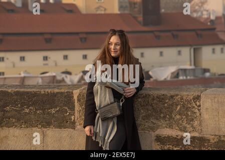 Prag, Tschechische Republik. 03-02-2021. Junge Modefrau auf der Karlsbrücke im Stadtzentrum von Prag im Winter mit einem schönen Sonnenuntergang. Stockfoto