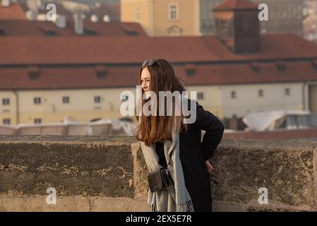 Prag, Tschechische Republik. 03-02-2021. Schöne Frau auf der Karlsbrücke im Stadtzentrum von Prag im Winter mit einem schönen Sonnenuntergang. Stockfoto