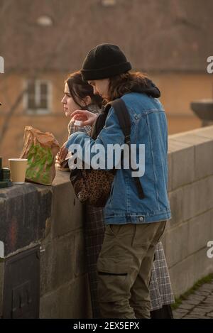 Prag, Tschechische Republik. 03-02-2021. Junges Paar essen auf der Karlsbrücke im Stadtzentrum von Prag im Winter mit einem schönen Sonnenuntergang. Stockfoto
