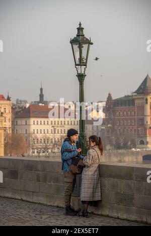 Prag, Tschechische Republik. 03-02-2021. Junges Paar essen auf der Karlsbrücke im Stadtzentrum von Prag im Winter mit einem schönen Sonnenuntergang. Stockfoto