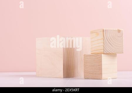Set aus Holzwürfelpodien auf weißem Holztisch und pastellrosa Wand für Präsentation und Produktpräsentation. Stockfoto