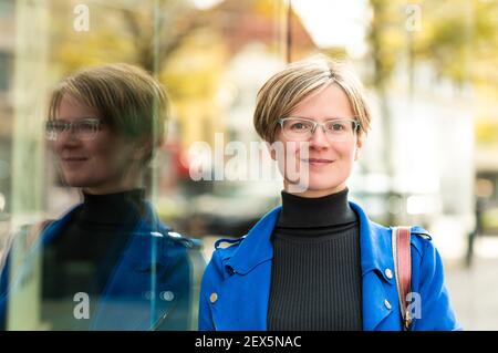 Porträt einer attraktiven dreißig Jahre alten weißen Frau posiert In einer traditionellen engen Straße Stockfoto