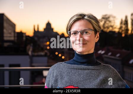 Porträt einer attraktiven dreißig Jahre alten weißen Frau posiert Auf einer Terrasse mit einem bunten Sonnenuntergang Hintergrund Stockfoto