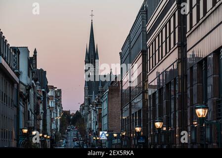 Molenbeek, Region Brüssel-Hauptstadt - Belgien - 11 23 2020: Die KBC-Bankfiliale und der Turm der Kirche Saint Remigius bei Sonnenaufgang Stockfoto