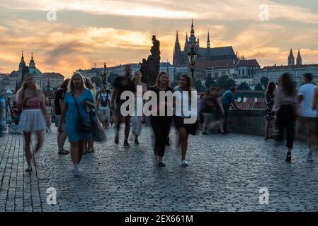 Prag - Tschechische Republik - 08 01 2020: Touristen im Sommer Kleidung zu Fuß über die Karlsbrücke in einer Sommernacht mit einem bunten Himmel Stockfoto