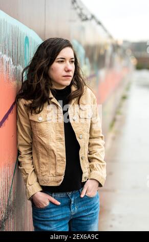 Halbkörperaufnahme einer attraktiven Brünette, posiert gegen eine bunte Wand in der Stadt Stockfoto