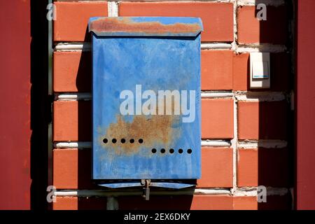 An einer roten Backsteinmauer hängt draußen ein blauer Briefkasten. Russische Briefkasten. Stockfoto