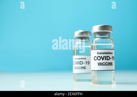 Fläschchen mit Covid - 19 Impfstoff vor blauem Hintergrund Stockfoto
