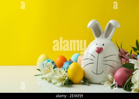 Osterhase, Eier und Alstroemeria Blumen vor gelbem Hintergrund Stockfoto