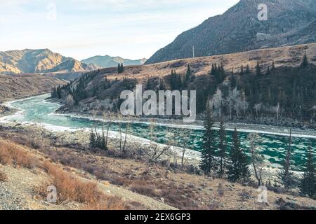 Schöne Winterlandschaft im Winter. Ungefrorener Gebirgsfluss fließt zwischen Bergen und Pinien. Stockfoto