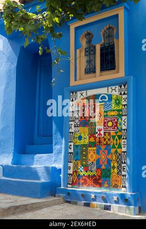 Marokko, Chefchaouen, 'die blaue Stadt' Architektur von weißen und indigoblauen Gebäuden mit Kunst an der Wand Stockfoto