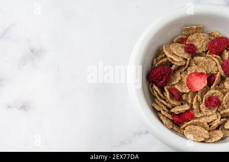 Draufsicht auf Schale mit Getreide und roten Beeren auf weißem Marmortisch, horizontal, mit Kopierraum Stockfoto