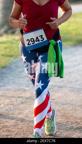 Ein Läufer Beine tragen American Flag Spandex beim Laufen ein 5K Rennen auf einem Trail rund um einen See. Stockfoto