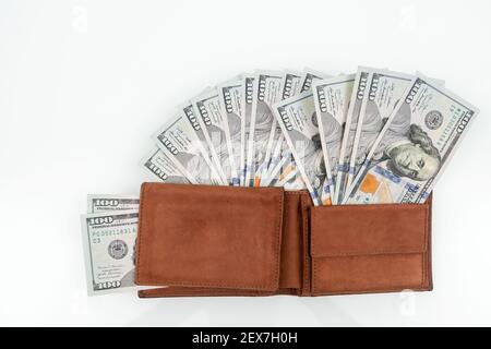 Eine Geldbörse voller Geld. Viele Banknoten in brauner Brieftasche auf weißem Hintergrund. Männliche Geldbörse mit Dollar. Flach liegend Stockfoto
