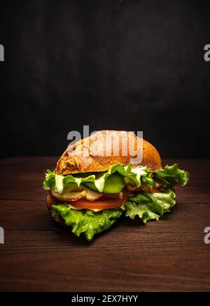 Sandwich mit Kräutern, Käse, Tomaten und Speck auf Holzgrund Stockfoto