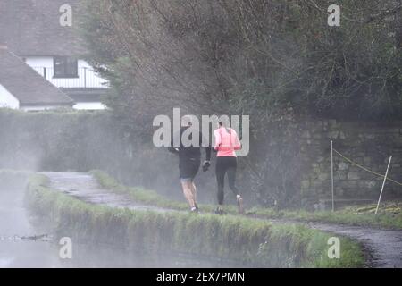 Loose Village, Kent, Großbritannien. Jogger, die an einem nebligen Morgen durch lockere Brooks auf dem Fußweg laufen Stockfoto