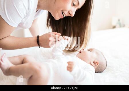 Stock Foto der jungen Mutter teilen niedlichen Moment mit ihrem kleinen Baby im Bett liegen. Stockfoto