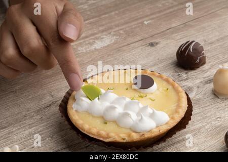 Gebäck in einem Studio, Details der Hand auf einem leckeren Zitronenkuchen, mit Gebäck Sahne verziert Stockfoto