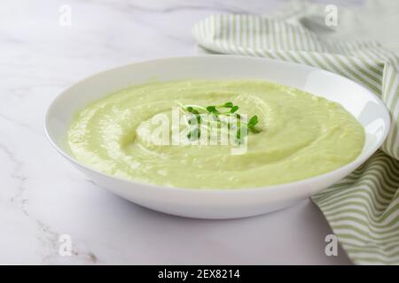 Klassische französische gekühlte Sahnesuppe Vichyssoise - warme oder kalte Kartoffel-Lauch-Suppe mit Microgreens auf Marmortisch Hintergrund gekrönt. Gesunde Ernährung Konzept Stockfoto