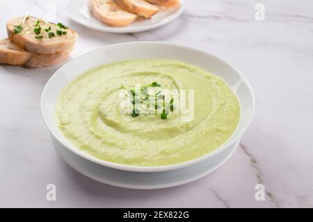 Klassische französische gekühlte Sahnesuppe Vichyssoise - warm oder kalt Kartoffellauch-Suppe mit Mikrogemüse in einer weißen Schüssel garniert Marmortisch Hintergrund und Stockfoto