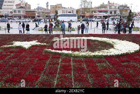 KONYA,TÜRKEI-APRIL 23:Menschen, die die türkische Flagge betrachten erstellt mit roten und weißen Tulpen April 23,2017 in Konya, Türkei Stockfoto