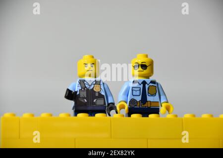 Zwei Lego-Minifiguren von US-Polizeibeamten standen hinter einem Gelbe Ziegelwand Stockfoto