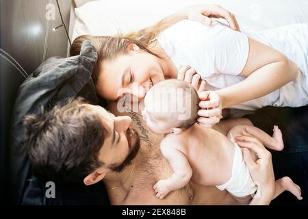 Stock Foto von jungen Paar teilen niedlichen Moment mit ihrem Baby im Schlafzimmer. Stockfoto