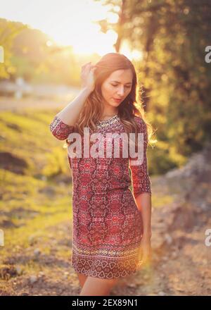 Porträt der jungen Frau in lässigen Sommerkleid, starke Sonnenuntergang Hintergrundbeleuchtung mit schönen Bokeh Stockfoto