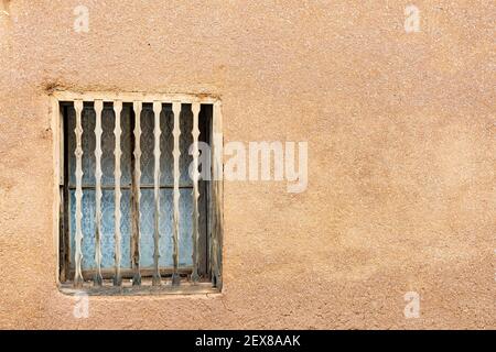 Alte südwestliche braune Adobe Wand und Fenster mit dekorativem Holz Spindeln Stockfoto