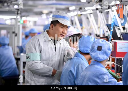 (210304) -- FUZHOU, 4. März 2021 (Xinhua) -- Chen Manku, ein Produktionslinienvorarbeiter aus der Autonomen Region Ningxia Hui im Nordwesten Chinas, führt Arbeiter bei einer Werkstatt in Fuzhou, südöstlich der Provinz Fujian in China, 3. Februar 2021. Seit 2018 kommen 459 junge Menschen aus verarmten Familien in Ningxia zur Fujian SCUD Senior Technical School, um ihre Fähigkeiten zu erlernen. Nach dem Abschluss werden sie in SCUD Elektronik-Unternehmen zu SCUD Group Limited verbunden arbeiten. In den letzten Jahren sind Gruppen von jungen Menschen aus Ningxia durch Trainingsprogramme nach Fujian gekommen, um mehr Fähigkeiten zu erlernen. (Xinhua/Jiang Keho Stockfoto