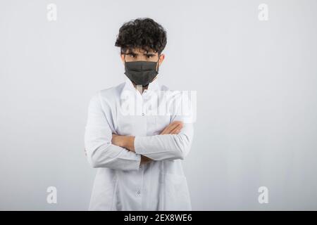 Junge Arzt trägt Maske und geben selbstbewussten Blick auf die Kamera Stockfoto