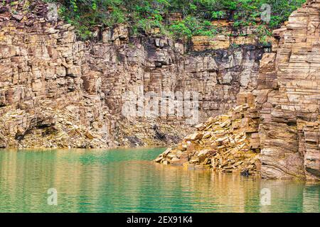 Schöne Landschaft mit sedimentären Felswänden mit goldenen Tönen und das Wasser des Sees zwischen den Felsen. Foto am Furnassee, Capitólio MG, Stockfoto