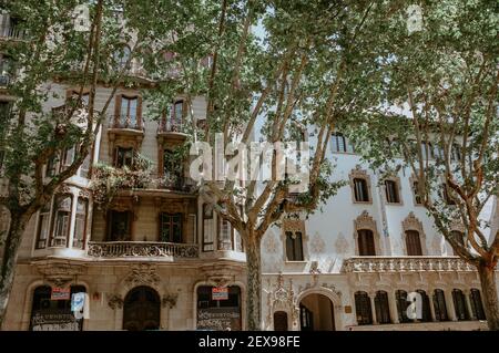 BARCELONA, SPANIEN - 01. Mai 2019: Wohnhaus hinter den Bäumen in Barcelona, Spanien Stockfoto