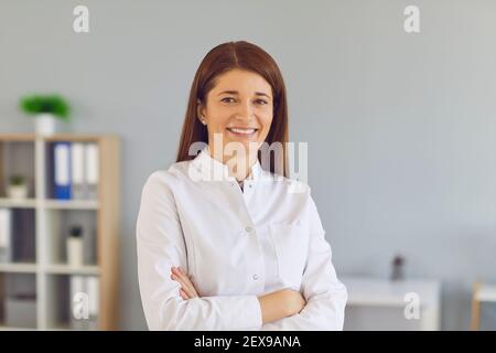 Porträt von positiv lächelnden jungen Arzt oder Online-Berater in Weiße Laborbeschichtung Stockfoto
