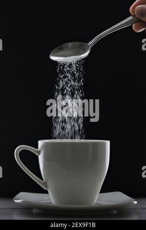 Tee Tasse oder Kaffee und Gießen Zuckerlöffel auf schwarz Hintergrund Stockfoto