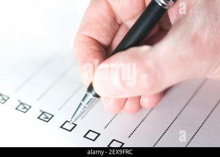 Nahaufnahme der Person, die die Checkliste mit dem Kugelschreiber abtickt Stockfoto