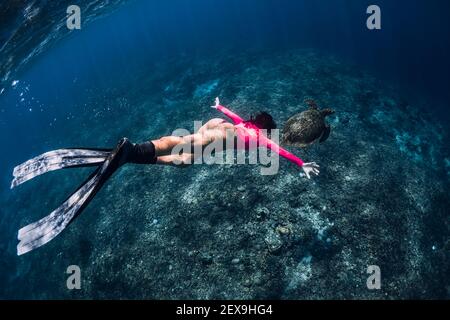Freediver Frau gleitet unter Wasser mit Schildkröte im Ozean. Schnorcheln mit grüner Meeresschildkröte. Stockfoto