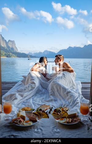 Pärchen beim Frühstück vor dem hölzernen schwimmenden Zimmer Besuch Khao Sok Nationalpark in Phangnga Thailand, Khao Sok Nationalpark, Cheow Lan See, Ratchaphapha Damm. Mann und Frau mittleren Alters Urlaub Stockfoto