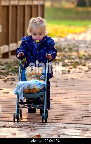 Nettes kleines Mädchen mit Puppenwagen Stockfoto