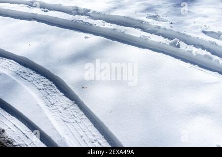 Autospuren im Schnee im Winter an einem sonnigen Tag Stockfoto