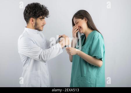 Arzt hilft lächelnde Krankenschwester trägt ihre Maske Stockfoto
