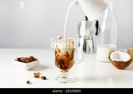 Kokosmilch mit Eiskaffee ins Glas gießen. Kalte Erfrischung Sommergetränk. Stockfoto