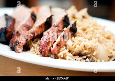 Glasiertes Schweinefleisch mit frischem Gemüse und geschnittenem Schweinehirt über schmutzigem Reis Stockfoto