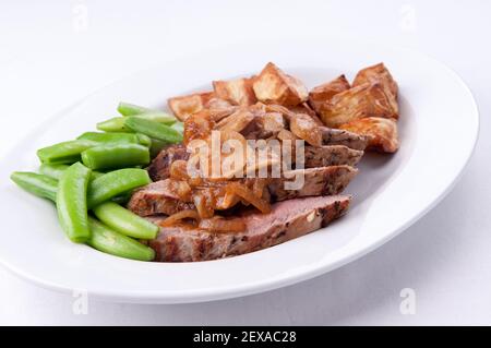 Gegrillte Schweinefilet-Medaillons mit Apfel und süßer Zwiebelsauce Serviert mit Kartoffeln und grünen Bohnen Stockfoto