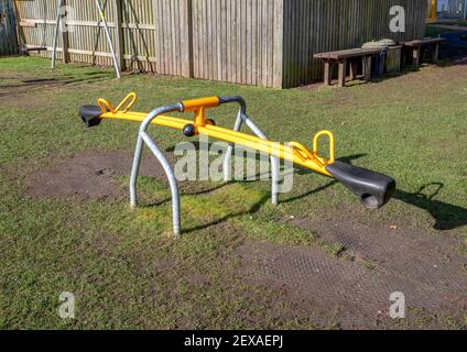 Eine gelbe Wippe in einem Spielplatz mit Gras und keine Menschen. Stockfoto