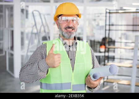 Lächelnder bärtiger Mann in Brille und Helm, der den Daumen hochgibt Stockfoto