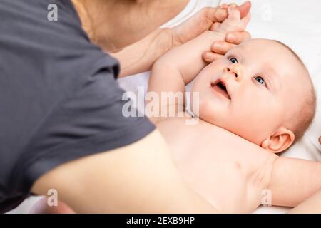 Fünf Monate Baby erhalten Massage-Therapie zu Hause während Coronavirus COVID-19 Pandemie Quarantäne. Masseur Manipulation der Arme des Kindes Stockfoto