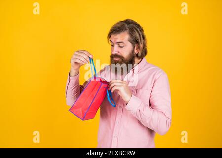 Schauen Sie einfach hier. Überrascht bärtigen Mann hält Geschenk-Paket. Alles gute zum Geburtstag oder Jubiläum. Feiertagsfeier. Überraschung für ihn. Shopping und Verkauf. Reifen brutalen Hipster mit Geschenk. Kaufen in Mall. Stockfoto