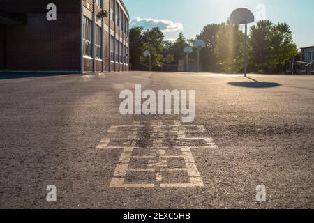 Schulgebäude und Schulhof am Abend. Hoppscotch Spiel auf Asphalt im Schulhof Spielplatz. Stockfoto