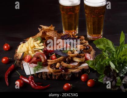 Ein großer Teller mit einer großen Auswahl an Biersnacks auf einem Holzbrett vor dunklem Hintergrund. Stockfoto